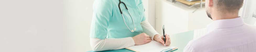 Doctor writing on a piece of paper whilst talking to a patient